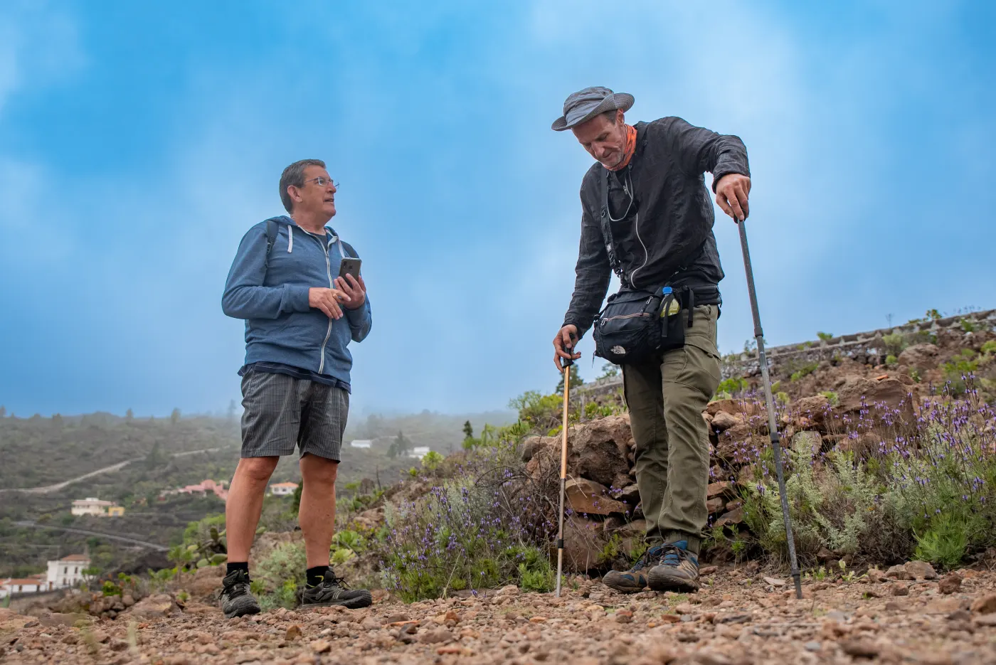 Dos senderistas en una ladera con la niebla subiendo por el valle