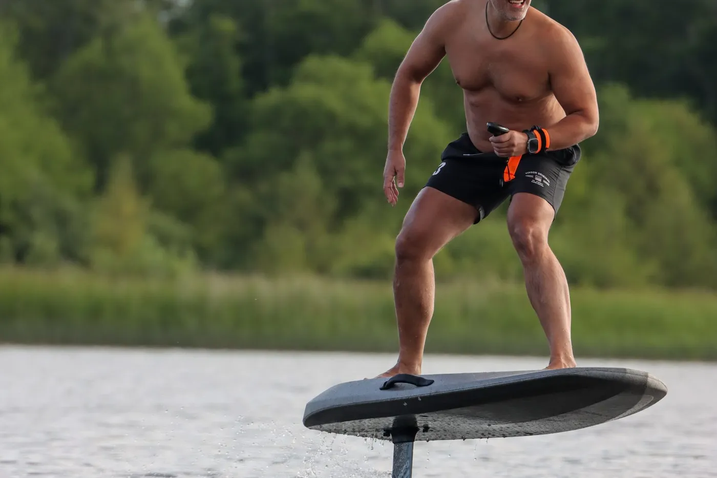 Person steht auf einem eFoil-Board und fliegt über das Wasser